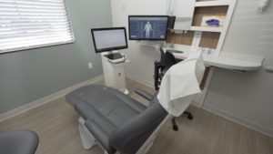A dentist's chair is in front of two screens, one of which is used by the best dentists for anxiety to monitor sedation dentistry patients.