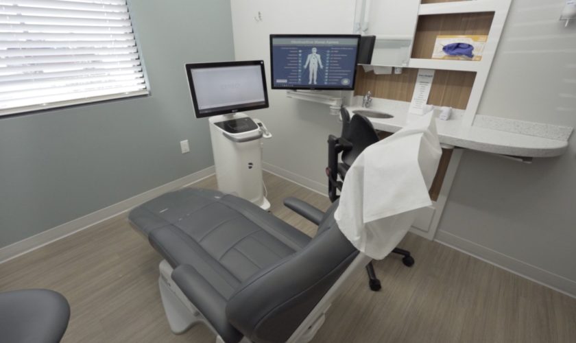 A dentist's chair is in front of two screens, one of which is used by the best dentists for anxiety to monitor sedation dentistry patients.