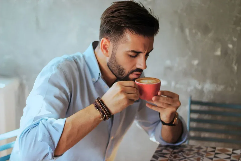 Person holding a hot cup of coffee with a concerned expression, illustrating tooth sensitivity to heat