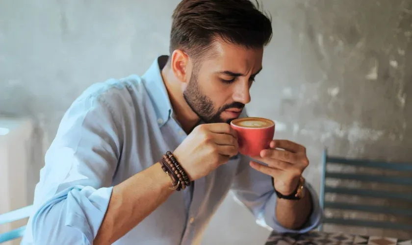 Person holding a hot cup of coffee with a concerned expression, illustrating tooth sensitivity to heat
