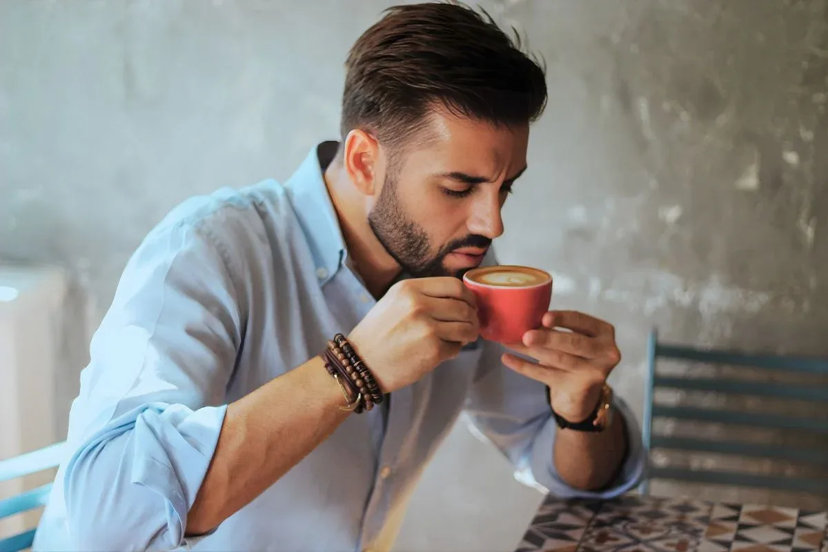 Person holding a hot cup of coffee with a concerned expression, illustrating tooth sensitivity to heat
