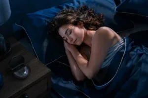 Woman asleep at night with a dental night guard in an open case on the bedside table